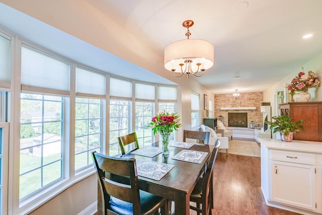 dining area featuring an inviting chandelier, baseboards, a fireplace, and dark wood finished floors