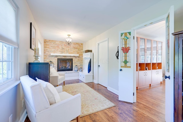 living area featuring baseboards, a stone fireplace, and wood finished floors