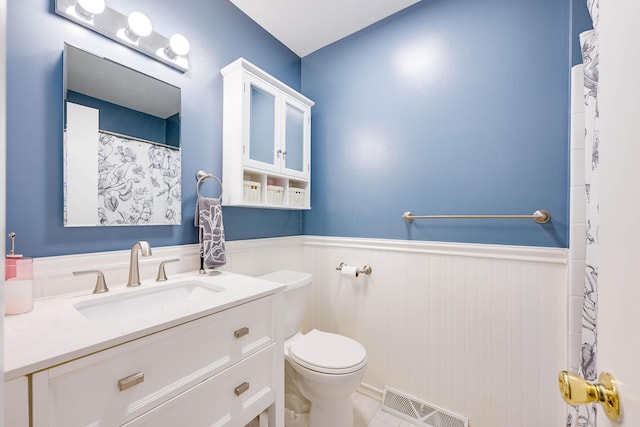 full bathroom featuring visible vents, vanity, wainscoting, curtained shower, and toilet