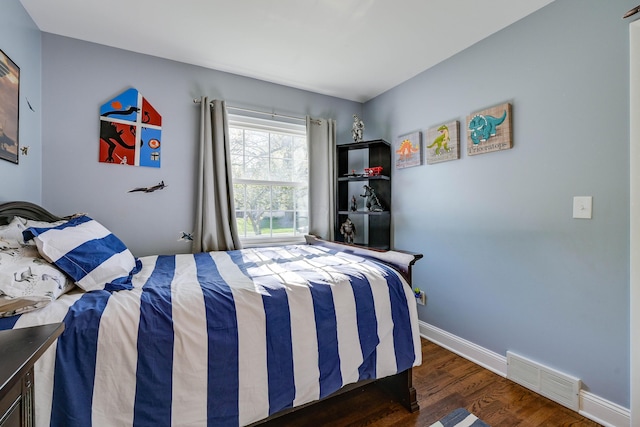 bedroom featuring baseboards, visible vents, and wood finished floors