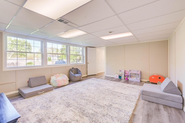 game room featuring a paneled ceiling, wood finished floors, and a wealth of natural light