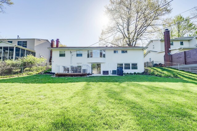 back of property featuring a fenced backyard, stucco siding, a lawn, and a deck