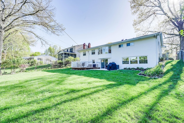 rear view of property with stucco siding, fence, a yard, and a wooden deck