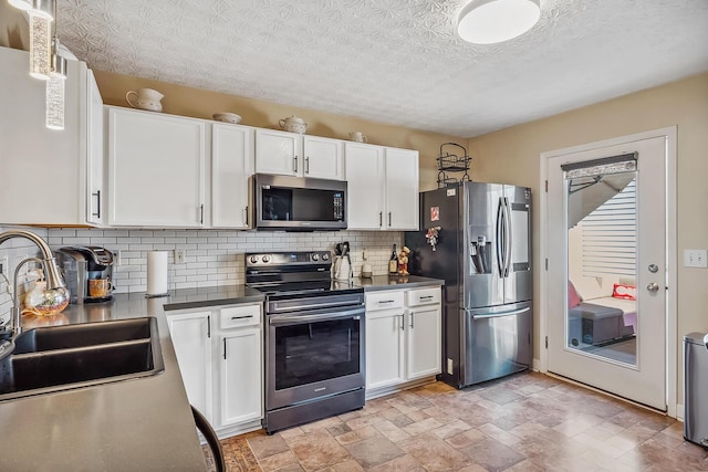 kitchen with a sink, appliances with stainless steel finishes, backsplash, and white cabinetry