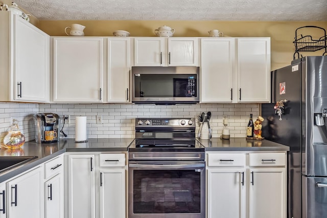 kitchen featuring appliances with stainless steel finishes, white cabinets, dark countertops, and tasteful backsplash