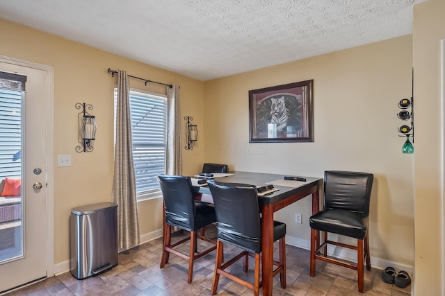 dining area featuring a healthy amount of sunlight, baseboards, stone finish flooring, and a textured ceiling