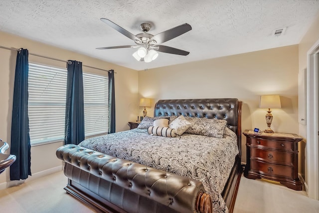 bedroom with a ceiling fan, a textured ceiling, visible vents, light colored carpet, and baseboards