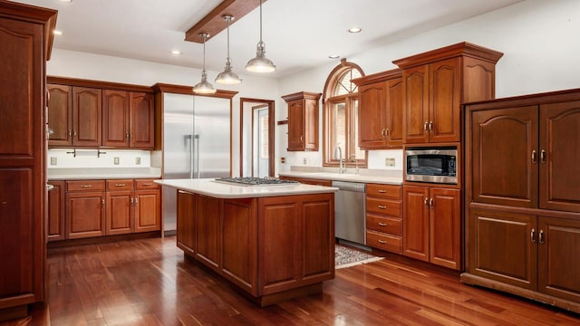 kitchen with built in appliances, dark wood-style flooring, a sink, and light countertops