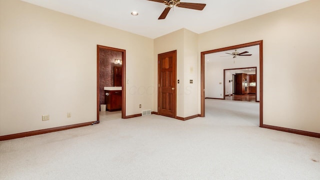 unfurnished bedroom featuring baseboards, ensuite bathroom, light carpet, and visible vents