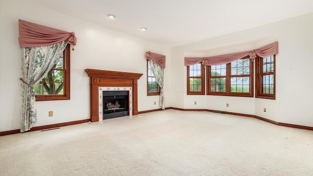 unfurnished living room featuring a healthy amount of sunlight, carpet flooring, and visible vents