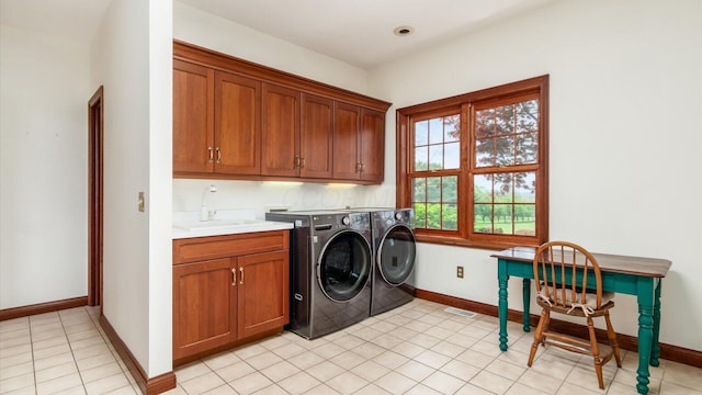 laundry room with baseboards, separate washer and dryer, a sink, cabinet space, and light tile patterned floors