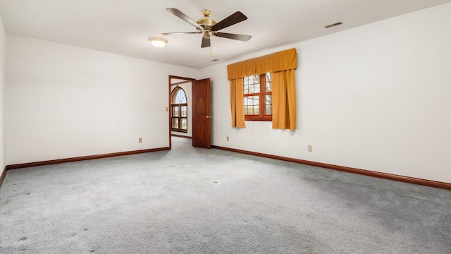carpeted spare room featuring baseboards, a ceiling fan, and visible vents