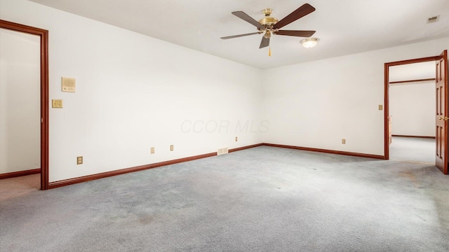 carpeted empty room featuring baseboards, ceiling fan, and visible vents