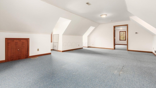 additional living space featuring visible vents, carpet, baseboards, and lofted ceiling