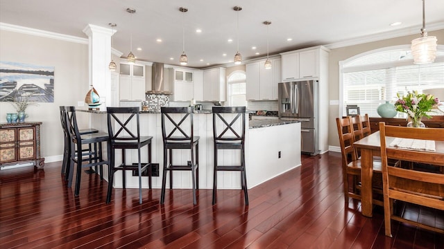 3555 Sellers Dr NE, Millersport, OH 43046 - kitchen featuring stainless steel fridge, wall chimney range hood, a breakfast bar area, white cabinetry, and crown molding