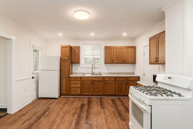 kitchen featuring a sink, brown cabinetry, white appliances, and dark wood-style flooring