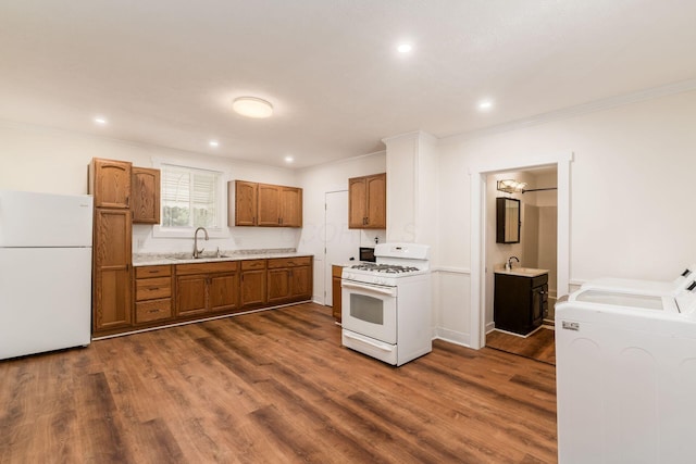 kitchen with dark wood finished floors, a sink, light countertops, ornamental molding, and white appliances