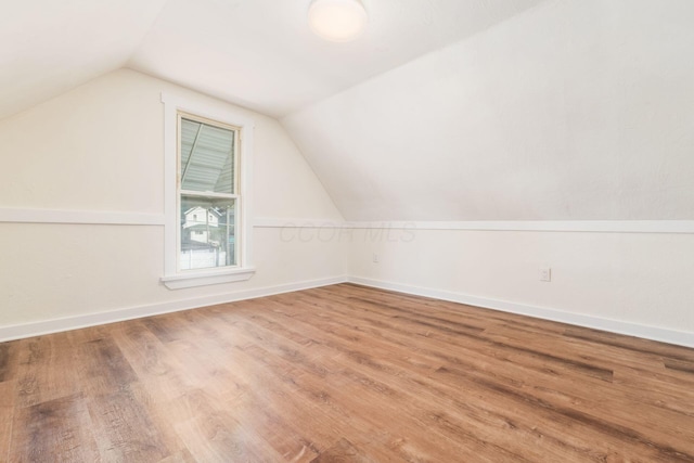 bonus room with baseboards, lofted ceiling, and wood finished floors