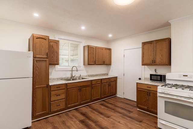 kitchen with a sink, brown cabinets, crown molding, and white appliances