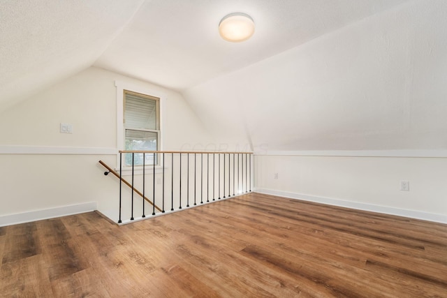 bonus room with baseboards, wood finished floors, and vaulted ceiling