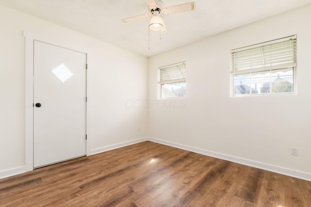 empty room featuring baseboards, ceiling fan, and wood finished floors