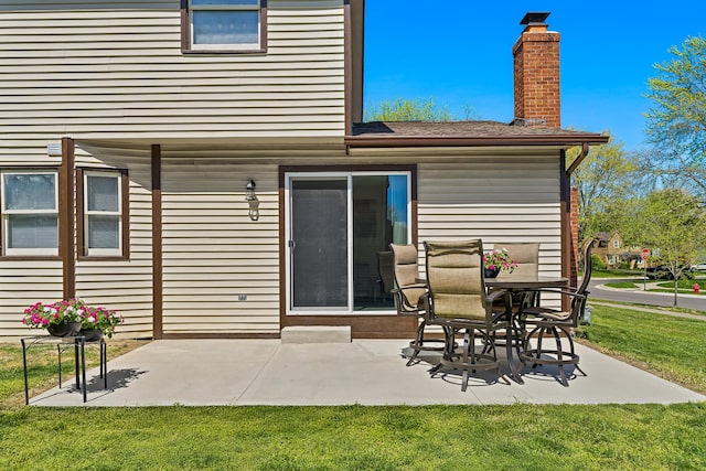 rear view of property featuring a lawn, a chimney, and a patio area