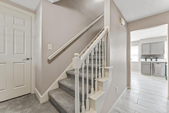 staircase with baseboards and a textured ceiling