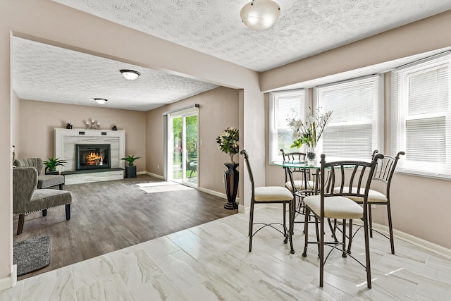 dining room with baseboards, a textured ceiling, and a glass covered fireplace