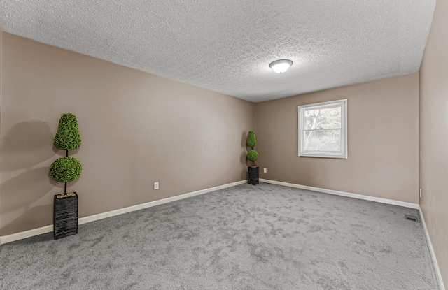 carpeted empty room featuring baseboards, a textured ceiling, and visible vents