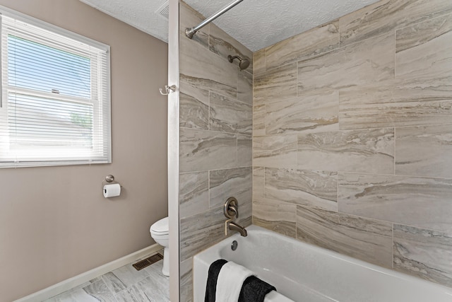 bathroom featuring visible vents, toilet, baseboards, washtub / shower combination, and a textured ceiling