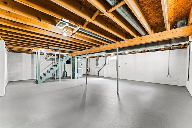 unfinished basement featuring stairway, concrete block wall, heating unit, and electric panel