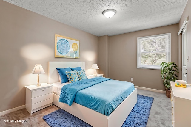 bedroom with light colored carpet, a textured ceiling, and baseboards