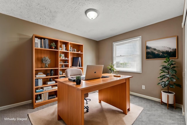 office area with a textured ceiling, baseboards, and light colored carpet