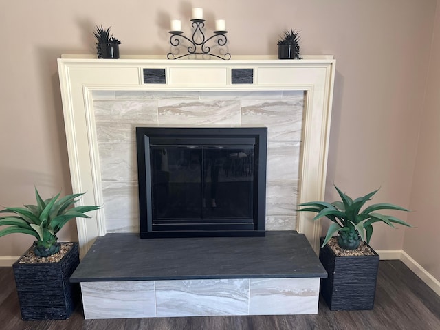 details with baseboards, a tiled fireplace, and wood finished floors