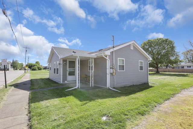 bungalow-style house featuring roof with shingles and a front yard