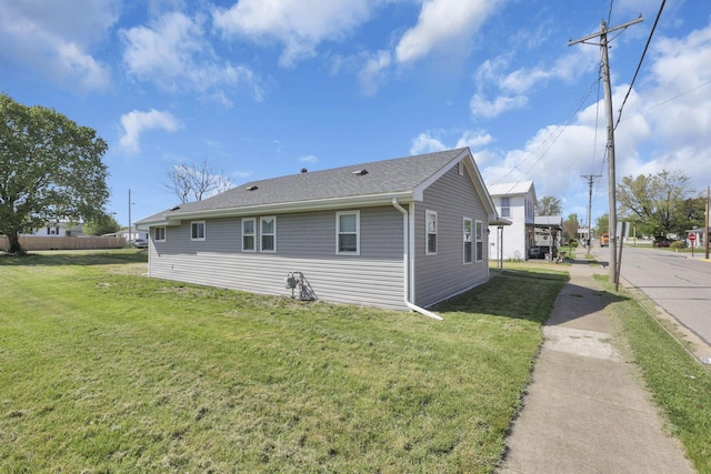view of property exterior with a yard and a shingled roof