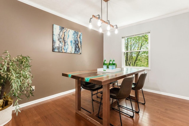 dining area featuring crown molding, baseboards, and wood finished floors