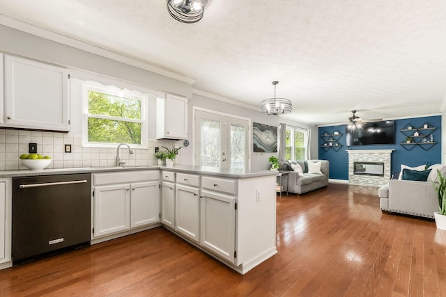 kitchen featuring ornamental molding, a peninsula, a fireplace, dishwashing machine, and white cabinetry