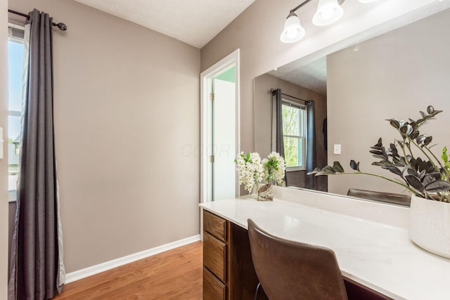 bathroom featuring baseboards, wood finished floors, and vanity