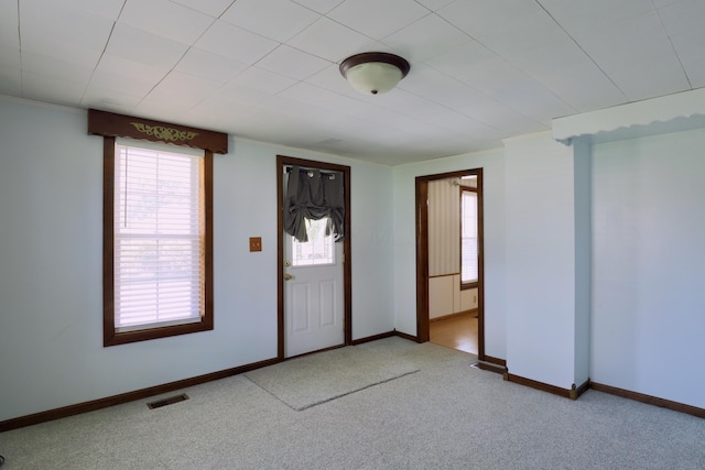 carpeted entryway featuring baseboards, ornamental molding, and visible vents