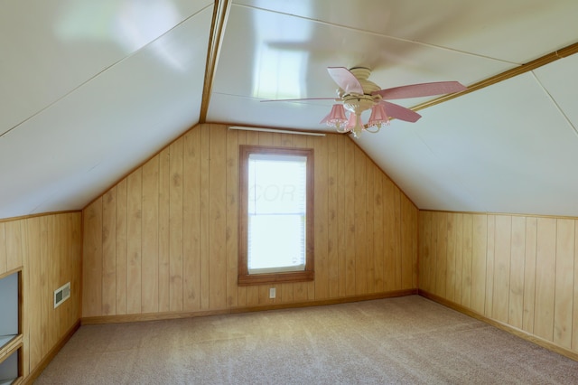 additional living space with wooden walls, ceiling fan, vaulted ceiling, and visible vents