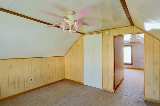 bonus room with wooden walls, carpet, a ceiling fan, and lofted ceiling