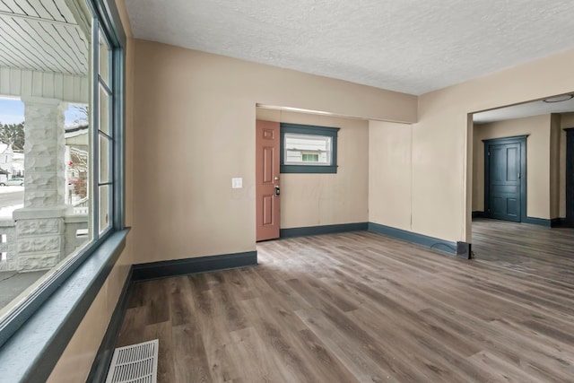 interior space featuring a healthy amount of sunlight, visible vents, wood finished floors, baseboards, and ornate columns