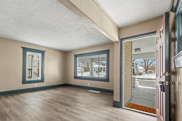 interior space with plenty of natural light, baseboards, a textured ceiling, and wood finished floors