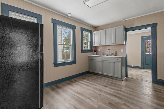 kitchen with baseboards, freestanding refrigerator, light wood finished floors, and a healthy amount of sunlight