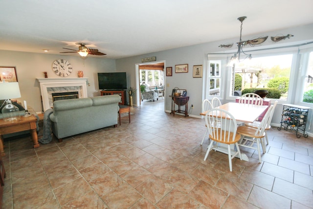dining space featuring a ceiling fan, baseboards, and a high end fireplace
