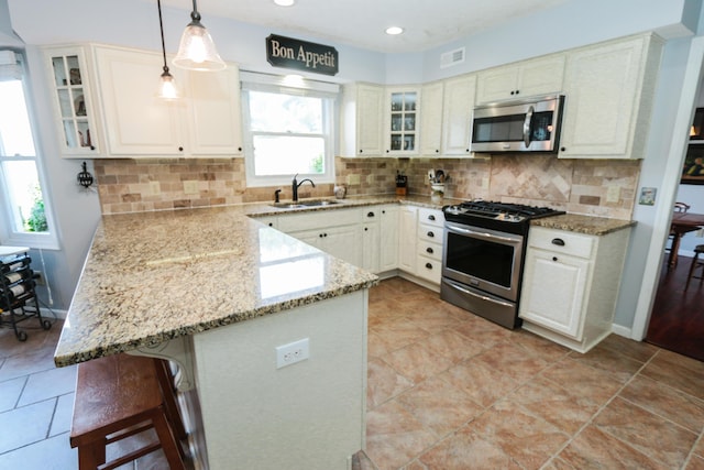 kitchen with visible vents, a sink, a kitchen breakfast bar, a peninsula, and appliances with stainless steel finishes
