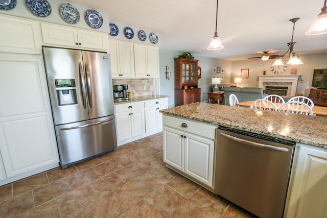 kitchen with stainless steel appliances, tasteful backsplash, ceiling fan, a premium fireplace, and hanging light fixtures