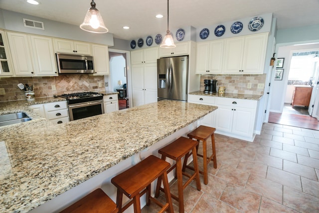 kitchen featuring appliances with stainless steel finishes, visible vents, light stone countertops, and backsplash