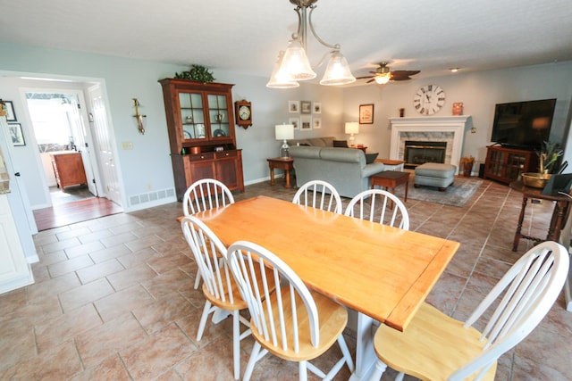 dining area with visible vents, baseboards, a ceiling fan, and a glass covered fireplace